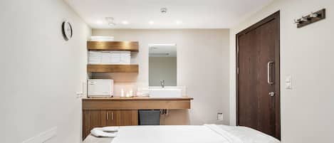 Un baño moderno con tocador de madera, lavamanos blanco y un espejo grande.