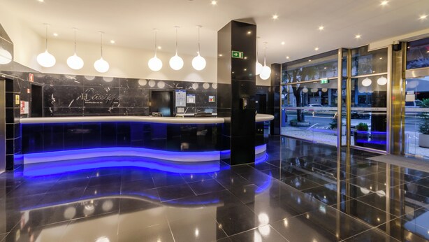 A modern hotel lobby with a reception desk, marble walls, and a blue-lit counter. - Olissippo Marques de Sa (Lisbon)