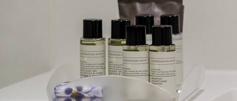 En udstilling af flasker med Scandinavian White body gel og shampoo på en hvid overflade.