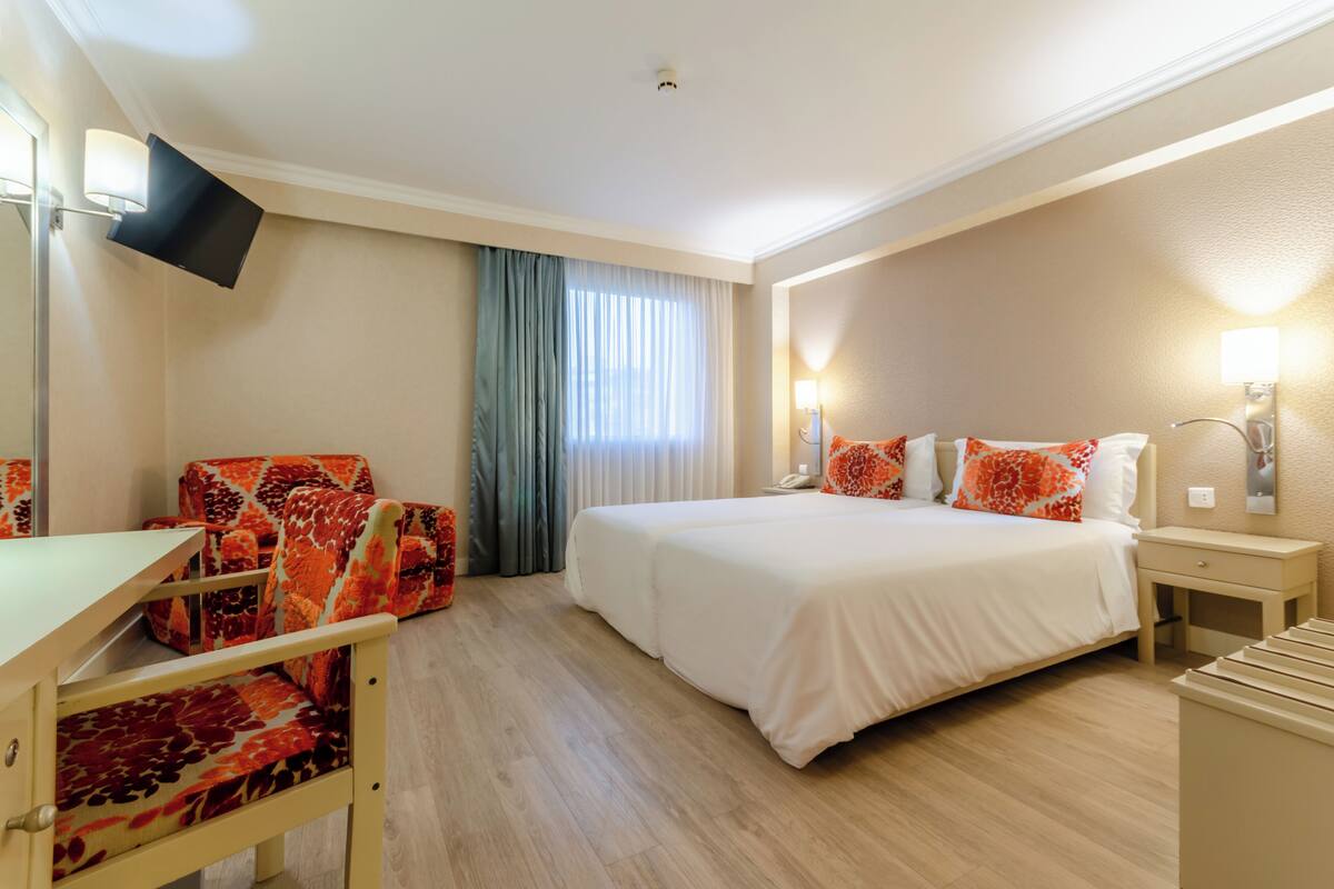 Ein Hotelzimmer mit Bett, Schreibtisch, Stuhl und Fernseher.