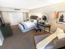 A hotel room with a bed, desk, chair, and a couch.
