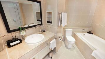 A modern bathroom with a large mirror, two sinks, a toilet, and a bathtub.