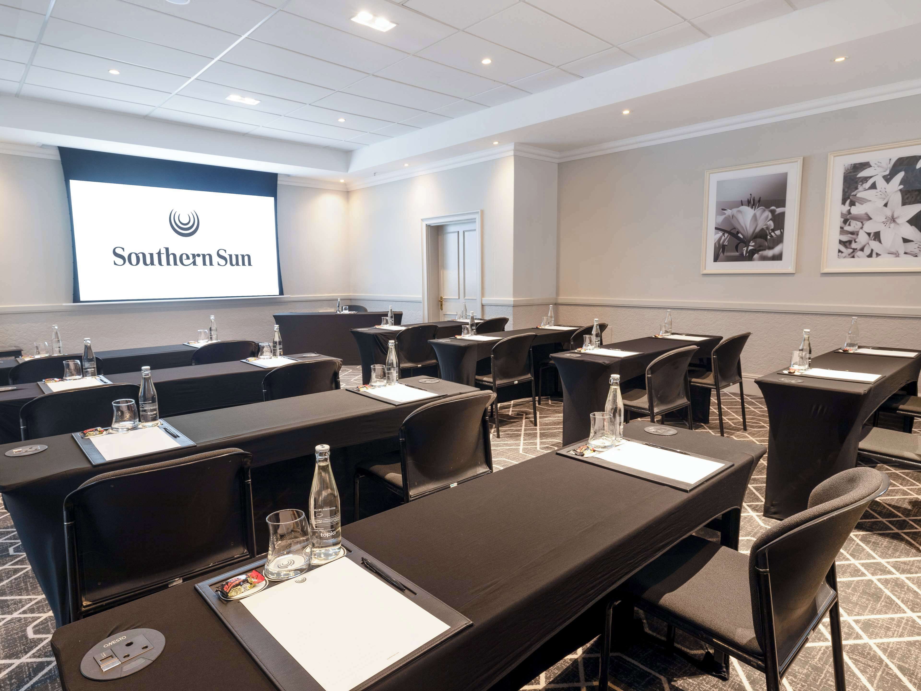 A conference room with tables, chairs, and a presentation screen displaying "Southern Sun".
