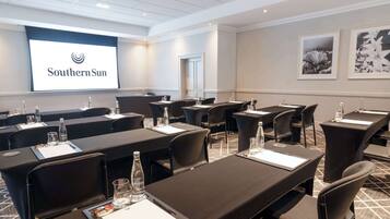 A conference room with tables, chairs, and a presentation screen displaying "Southern Sun".