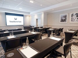 A conference room with tables, chairs, and a presentation screen displaying "Southern Sun".