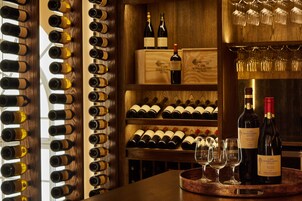 A wine cellar with wooden racks and shelves holding wine bottles and glasses.