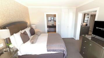 A hotel room with a bed, a desk, a TV, and a bathroom visible through an open door.