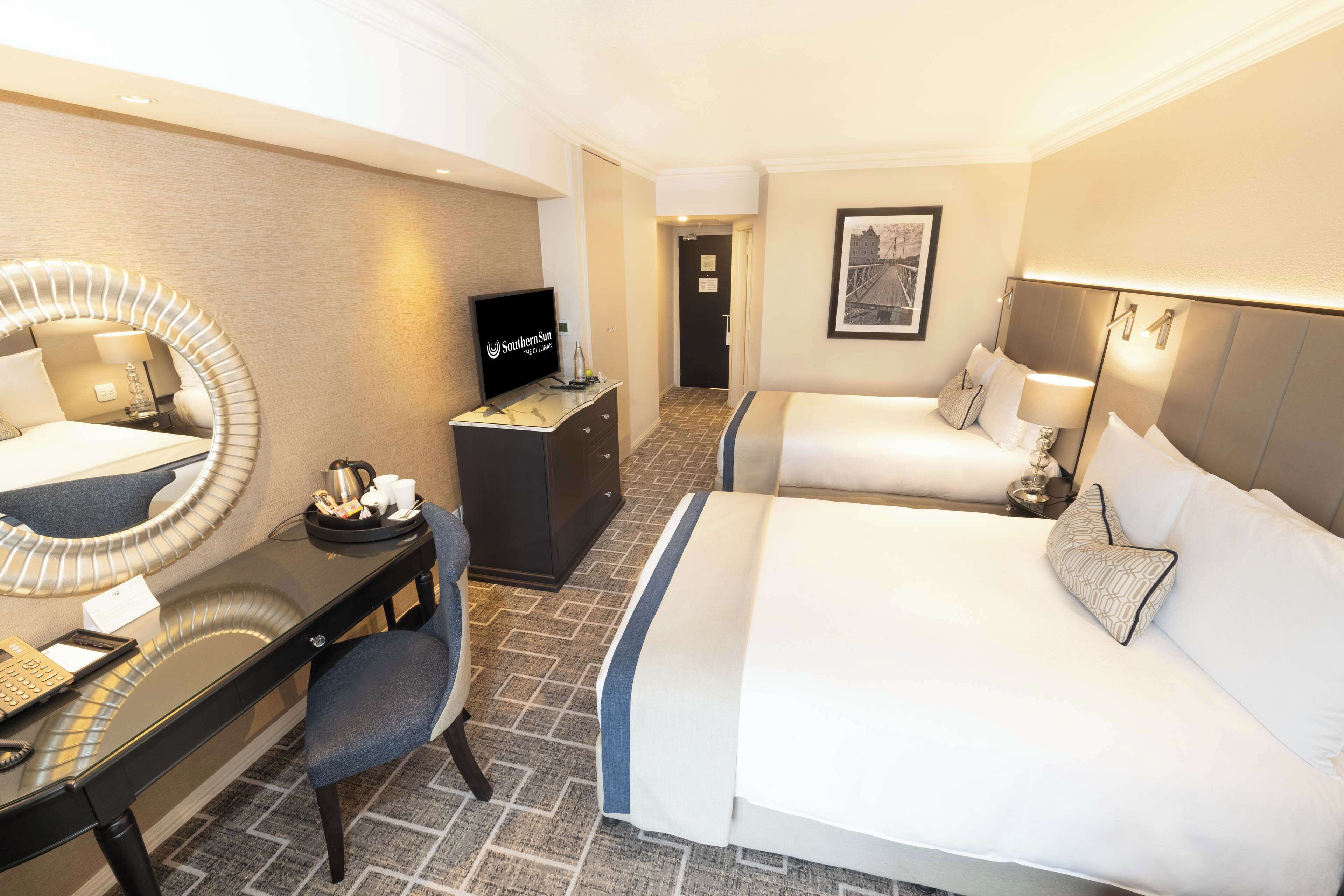 A hotel room with a bed, desk, chair, and a TV.