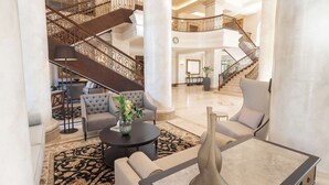 A spacious lobby with a grand staircase, comfortable seating, and a modern chandelier. - Southern Sun The Cullinan (Cape Town)