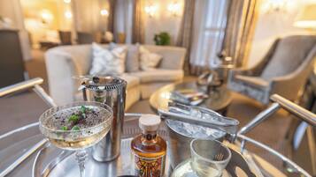 A tray with a martini glass, a bottle of liquor, a small bowl with herbs, and a shot glass.