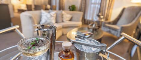 A tray with a martini glass, a bottle of liquor, a small bowl with herbs, and a shot glass.