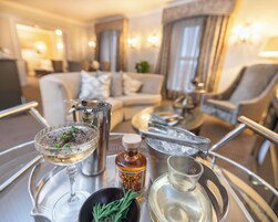 A tray with a martini glass, a bottle of liquor, a small bowl with herbs, and a shot glass.