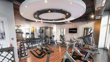 A gym with cardio machines, weightlifting equipment, and a TV screen displaying 'Southern Sun The Culinarian'.