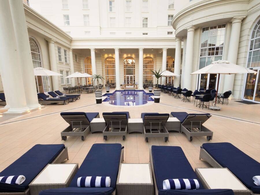 Una piscina al aire libre, sombrillas, sillones reclinables de piscina