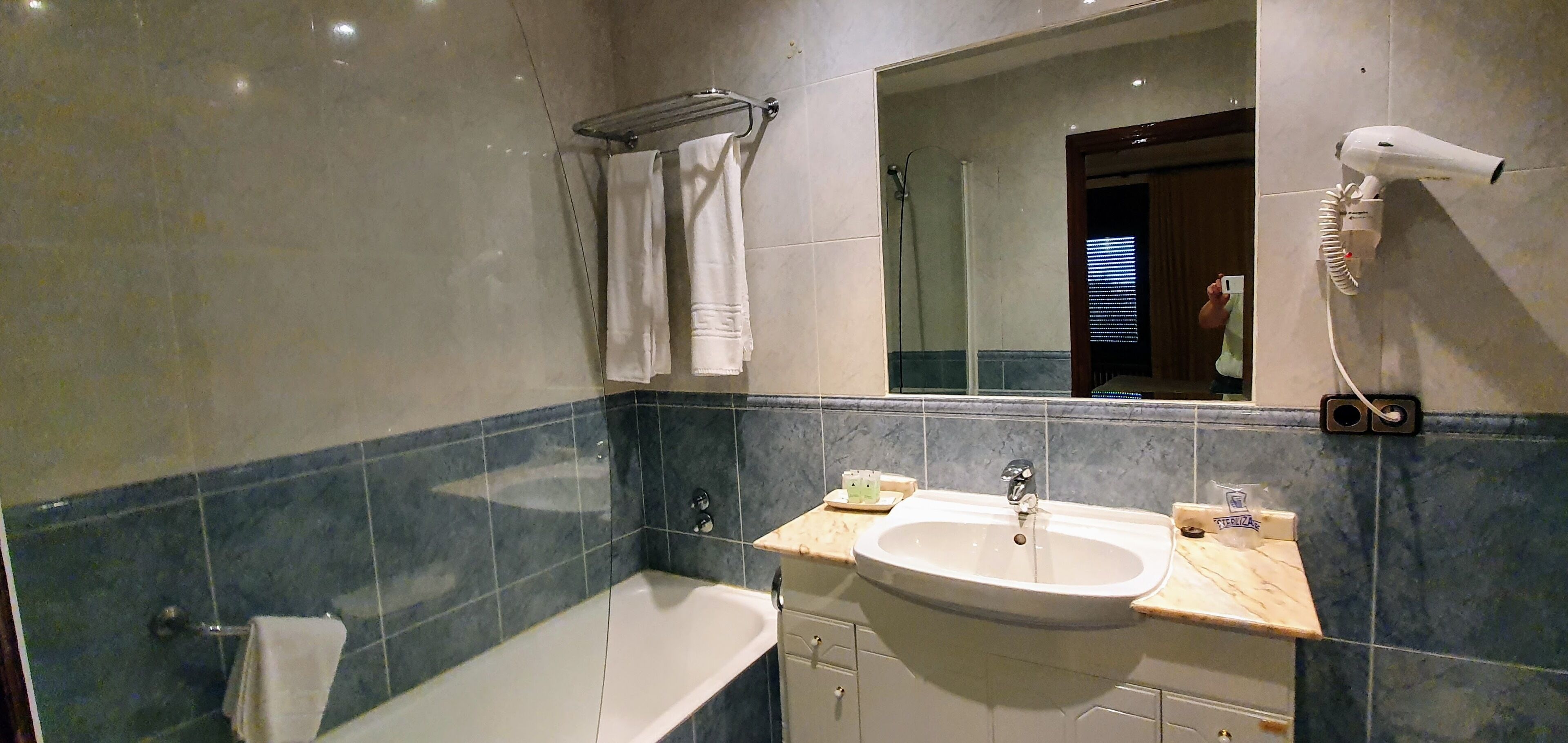 A bathroom with a bathtub, a sink, a towel rack, and a hairdryer.