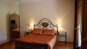 Un dormitorio con una cama, dos mesitas de noche, un espejo y una puerta.