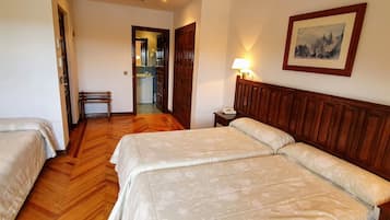 A hotel room with two beds, a wooden headboard, a bedside table with a lamp, and a framed picture on the wall.