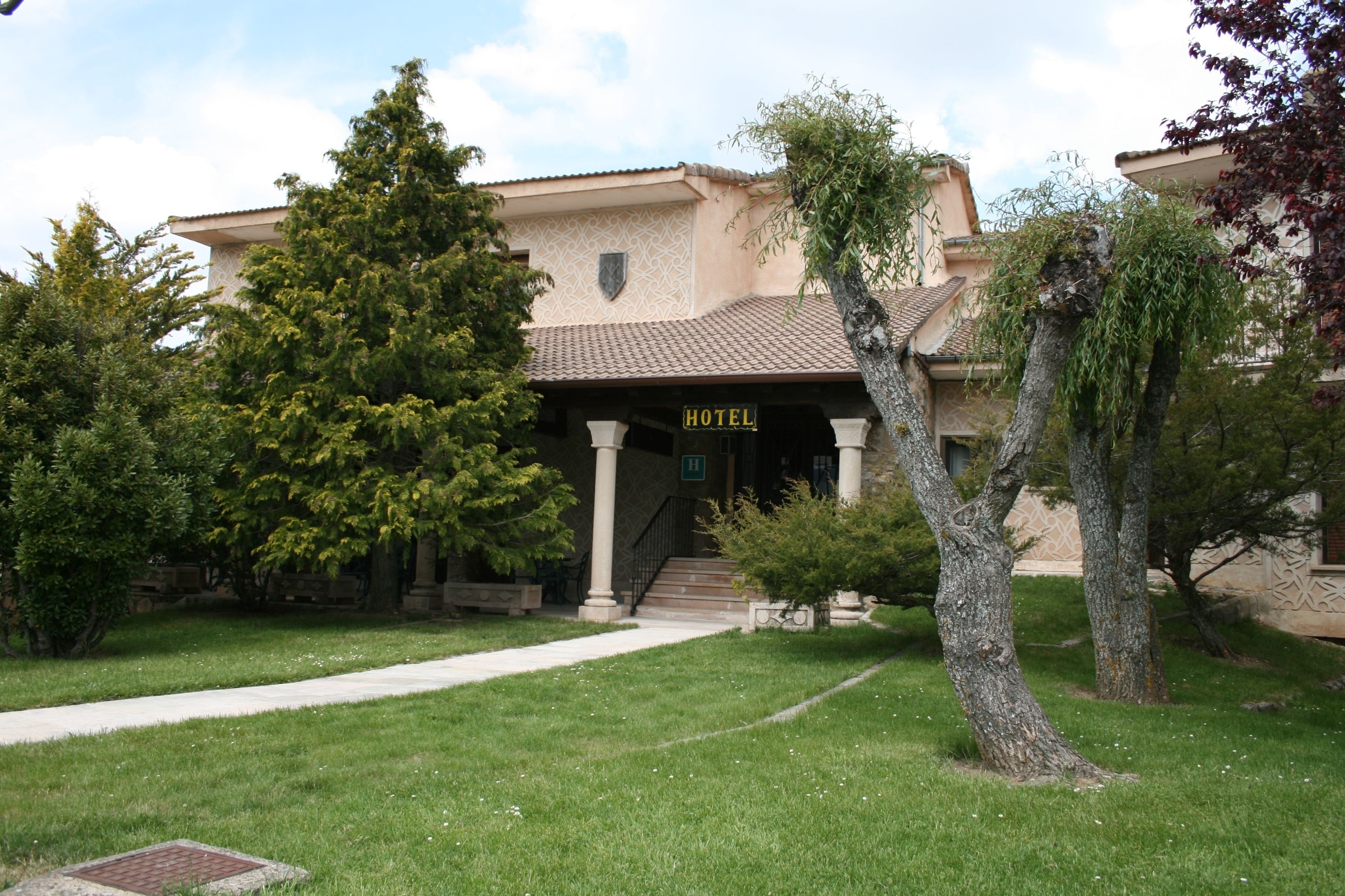 A hotel with a signboard, a paved entrance, and a well-maintained lawn.