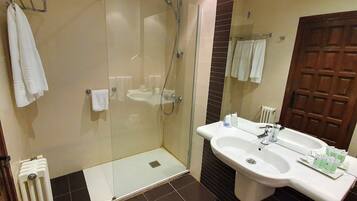 Un bany amb dutxa de vidre, un lavabo i un mirall.