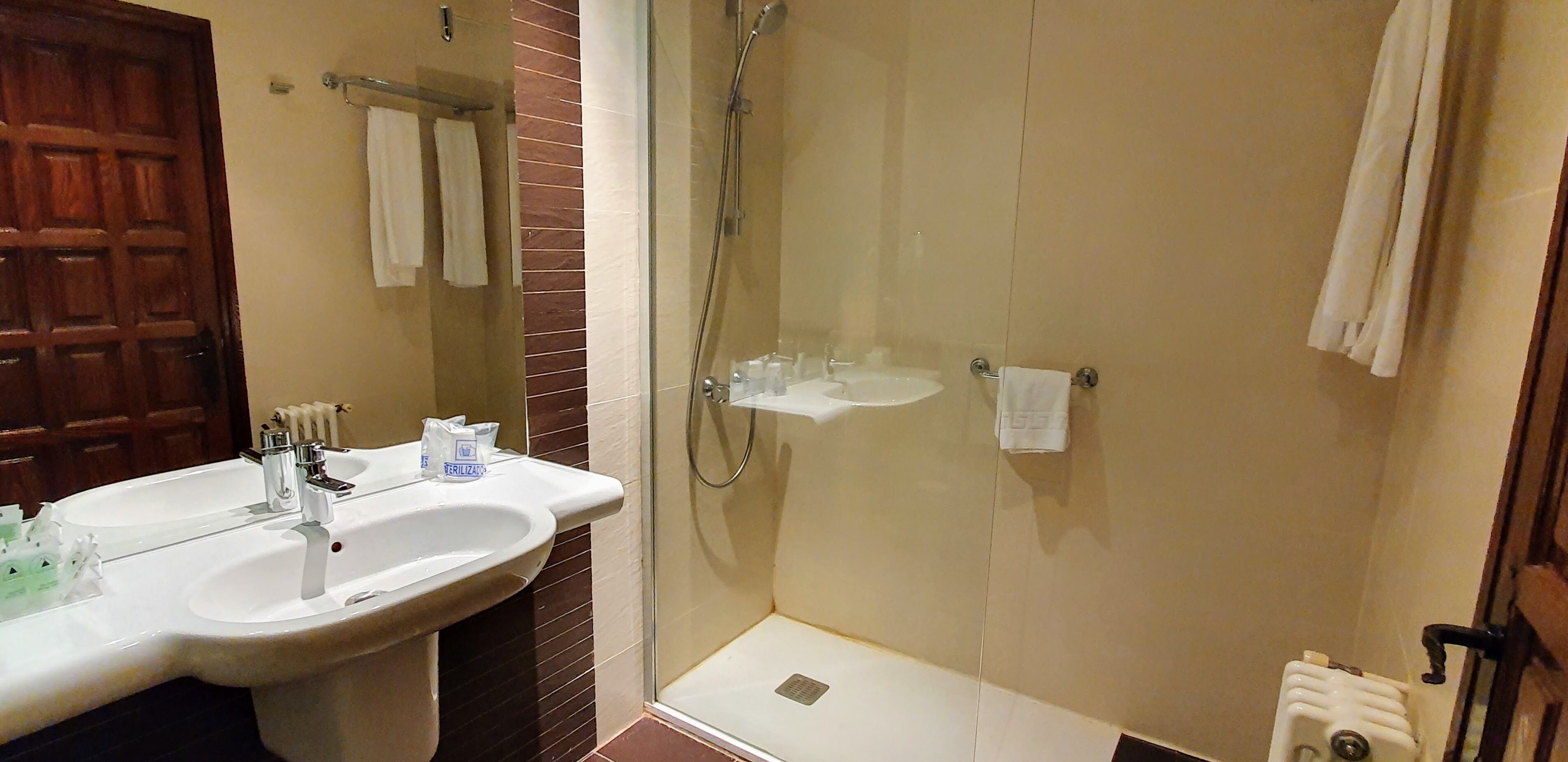 Un baño con dos lavamanos, una ducha y un inodoro.