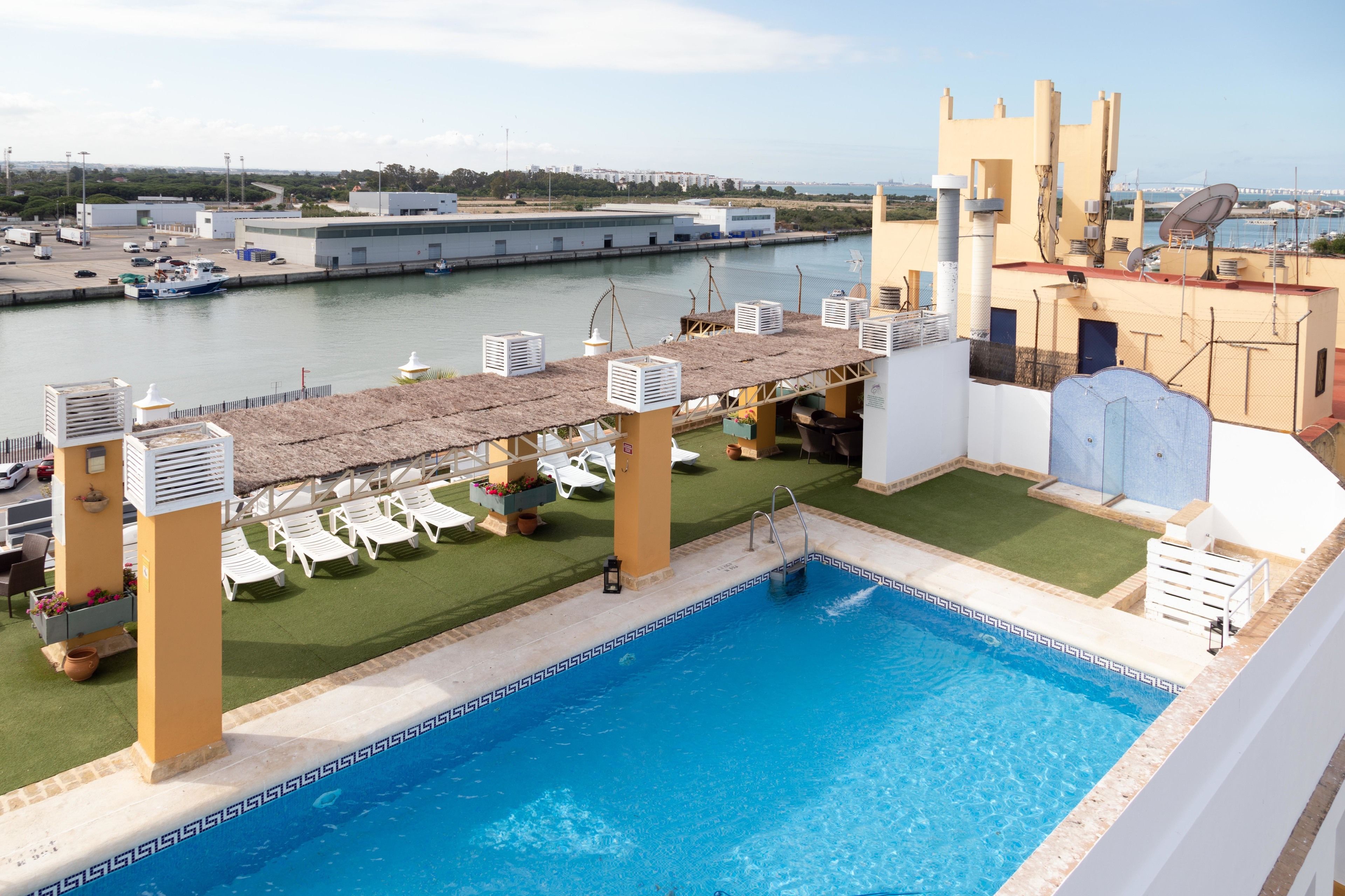 A rooftop pool with a view of the marina and buildings in the background.