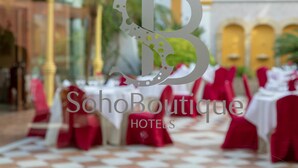 Een venue van SohoBoutique Hotels met tafels gedekt voor dineren, rode stoelen en een geruit vloertapijt.