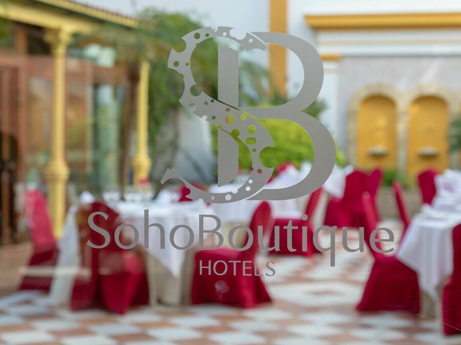 A SohoBoutique Hotels venue with tables set for dining, red chairs, and a checkered floor pattern.