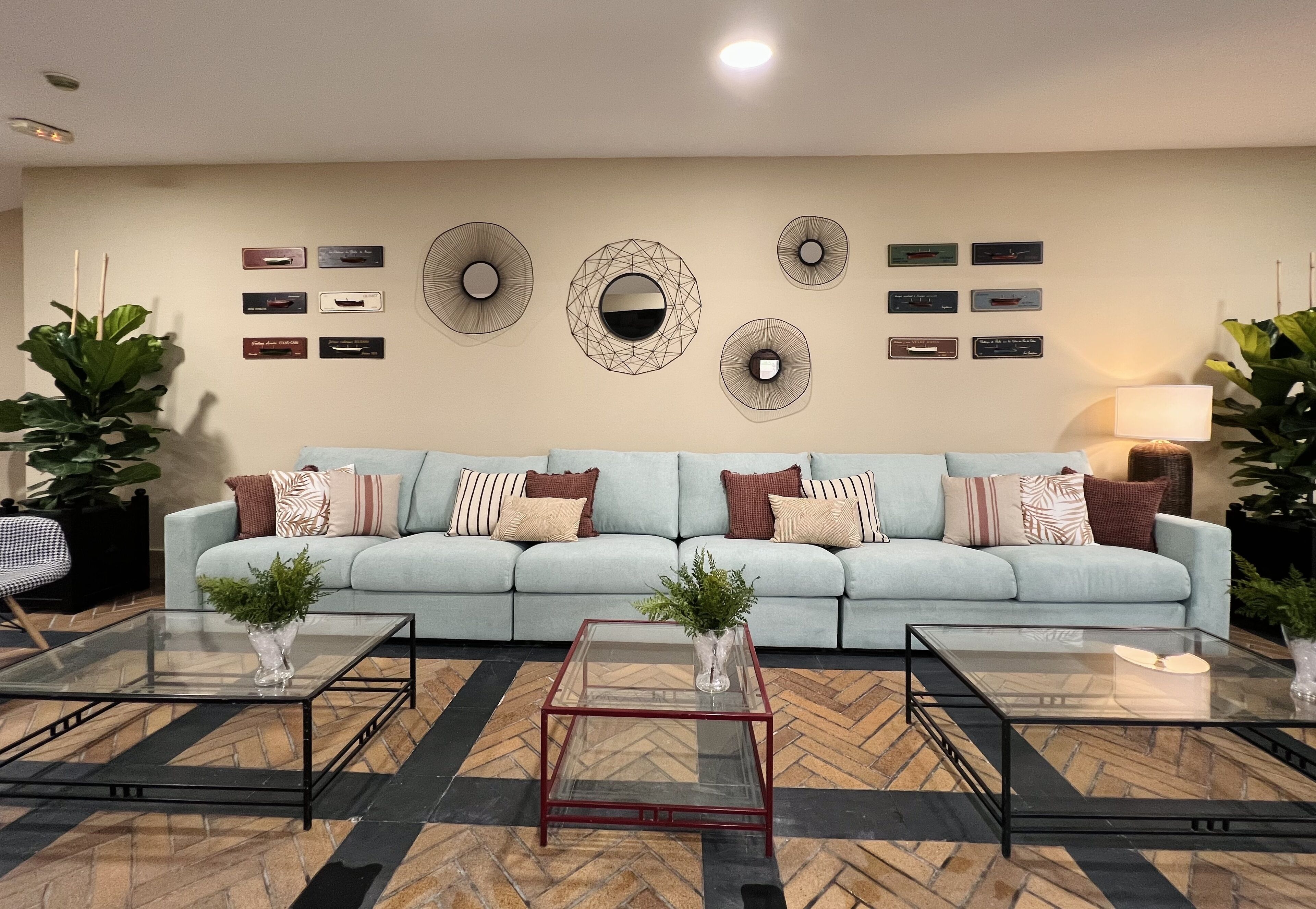 A living room with a light blue sofa, two glass coffee tables, and decorative wall art.
