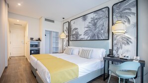 Een moderne slaapkamer met een bed, nachtkastje, stoel en kunstwerk aan de muur.