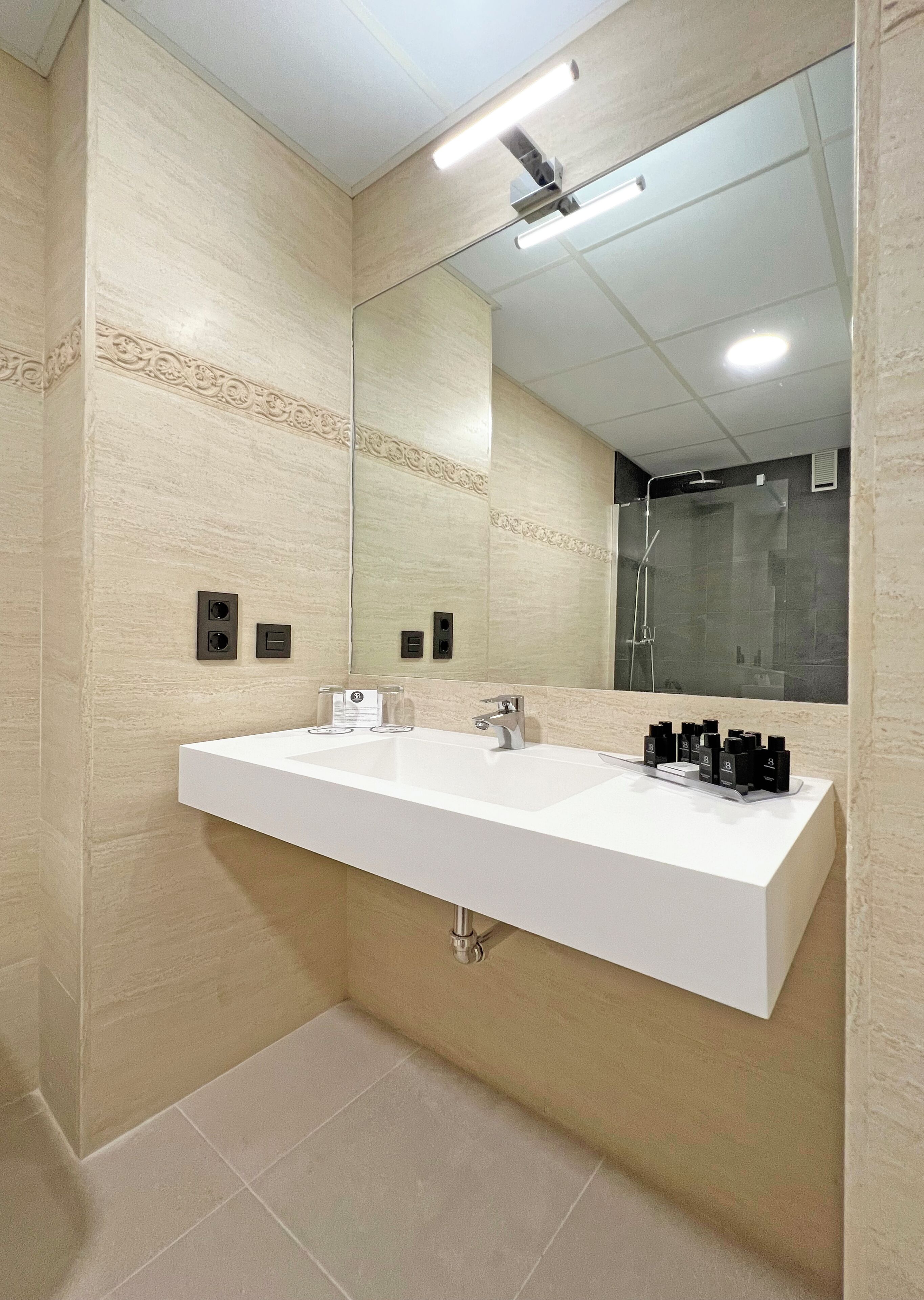 Un baño moderno con un espejo grande, dos lavamanos y una ducha.