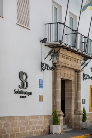 Fachada de hotel con un balcón, un cartel que dice "Solobo Boutique Hotels" y dos macetas con plantas.