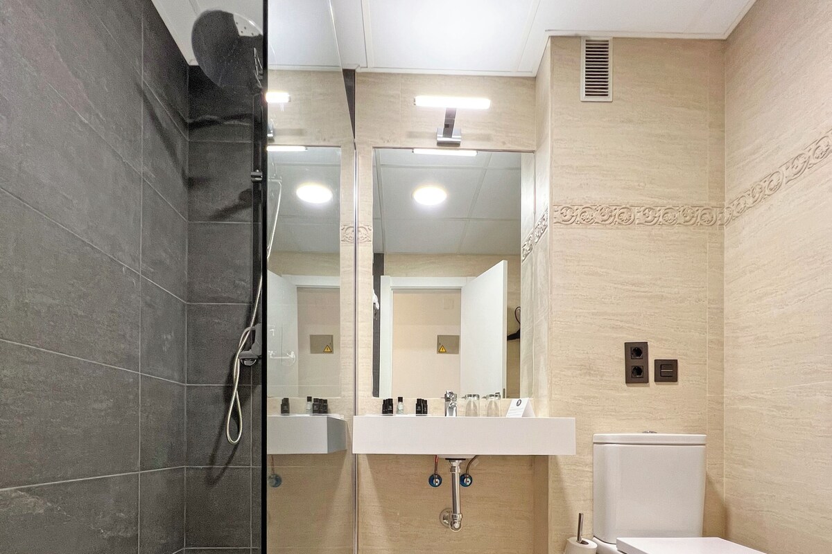 A modern bathroom with a glass shower enclosure, a white toilet, and a vanity with a mirror.