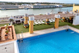 Una piscina al aire libre, sombrillas, sillones reclinables de piscina