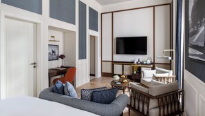 Habitació d'hotel moderna amb un llit gran, un sofà, un escriptori amb televisió de pantalla plana i zona de dinar.