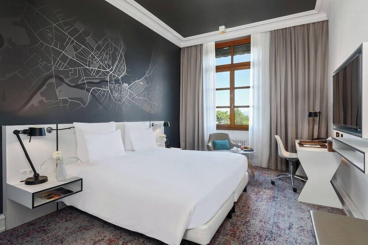 Habitación de hotel con una cama grande, un escritorio, una silla, un televisor y un mapa en la pared.
