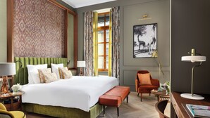 Habitació d'hotel amb un llit gran, una taula de treball, una cadira i una finestra amb cortines.