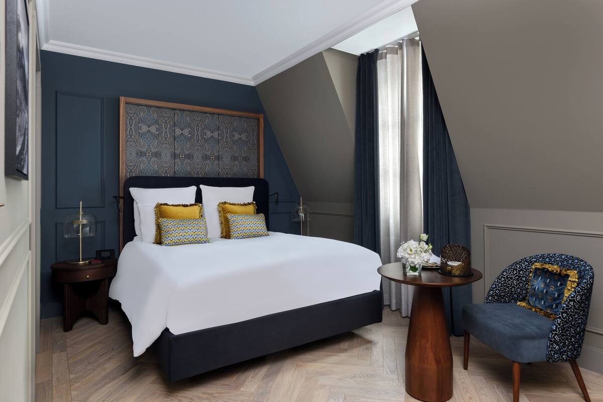 Un dormitorio con una cama grande, una mesita de noche, una silla y un panel decorativo en la pared.