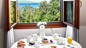 Taula de l'esmorzar amb croissants, un pastís decorat amb fruita i un bol de baies, amb una vista panoràmica de fons.