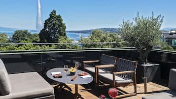 Eine Dachterrasse mit Außenplätzen, einem Tisch mit Speisen und Getränken und Blick auf das Meer sowie einen Leuchtturm.