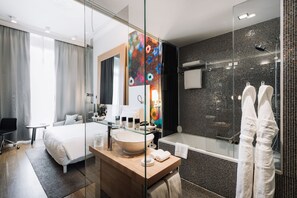 A modern hotel room with a large bed, a glass-enclosed shower, a wooden vanity, and a large mirror. - Hotel Metropole Geneve (Geneva)