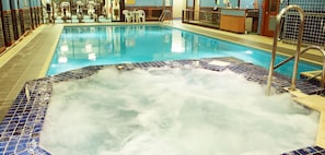 Une piscine intérieure dotée d’un espace avec jacuzzi, entourée de murs carrelés et comprenant un comptoir d’accueil.