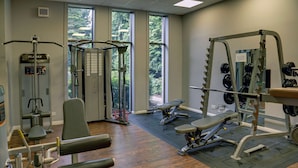 Une salle de sport équipée de divers appareils d’exercice, dotée de grandes fenêtres et d’un plancher en bois.