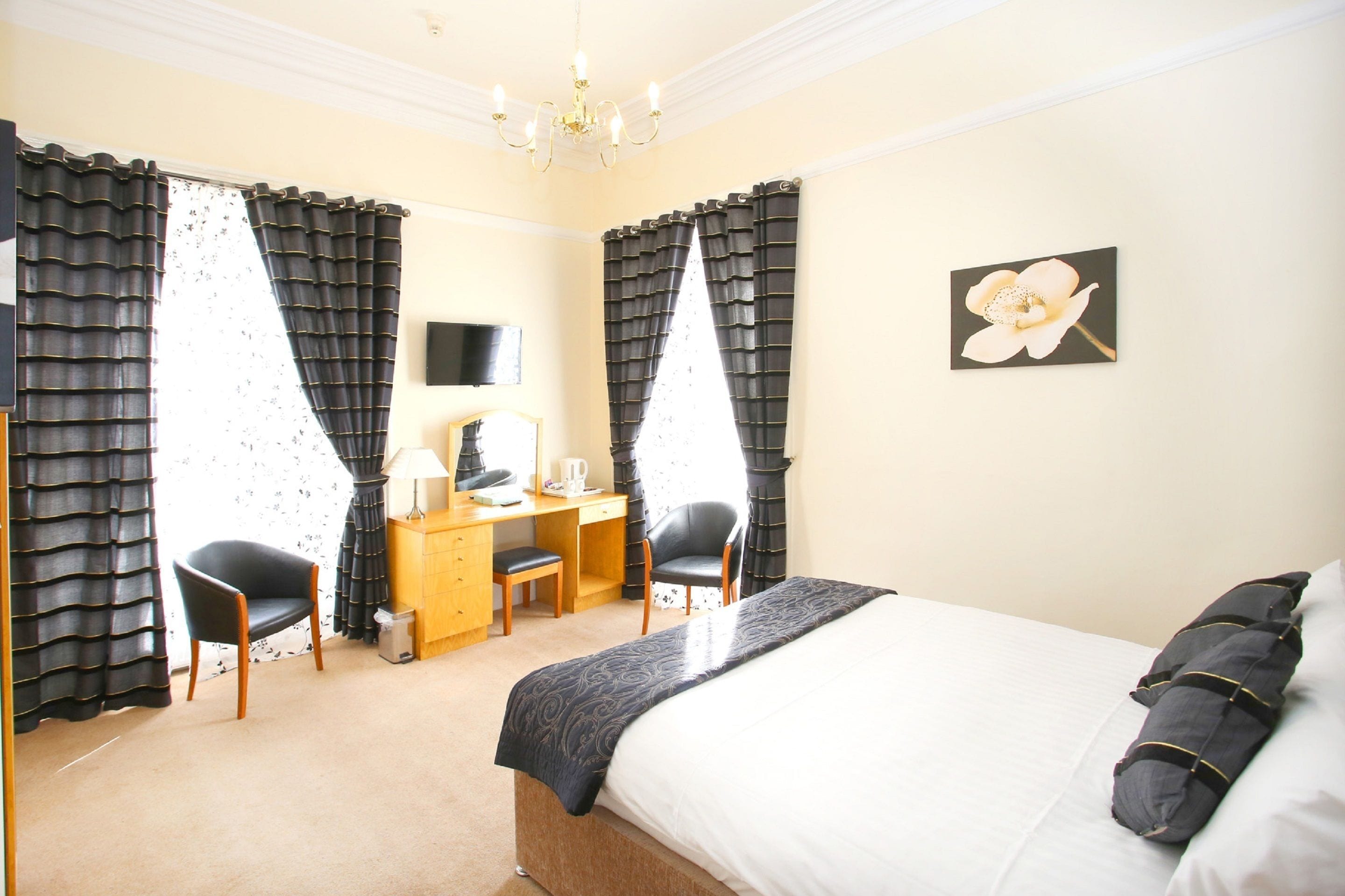 A hotel room with a bed, two chairs, a desk, and a television.