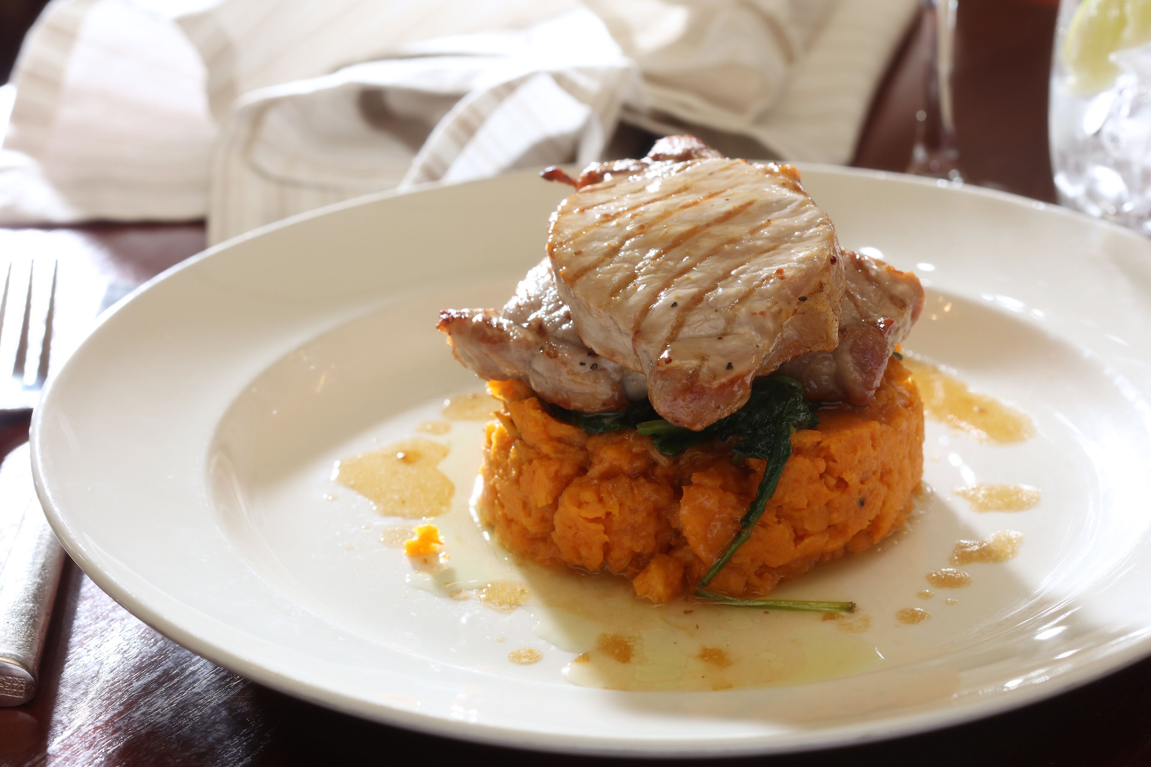 A plate of food with a piece of meat on top of mashed potatoes.