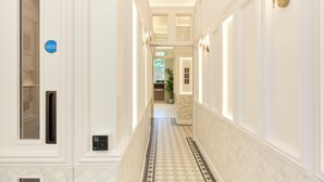 A hotel hallway with a check-in desk, a reception area, and a potted plant. - The Edwin Hotel (London)
