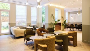 A spacious lounge area with comfortable seating, large windows, and a modern chandelier. - The Edwin Hotel (London)