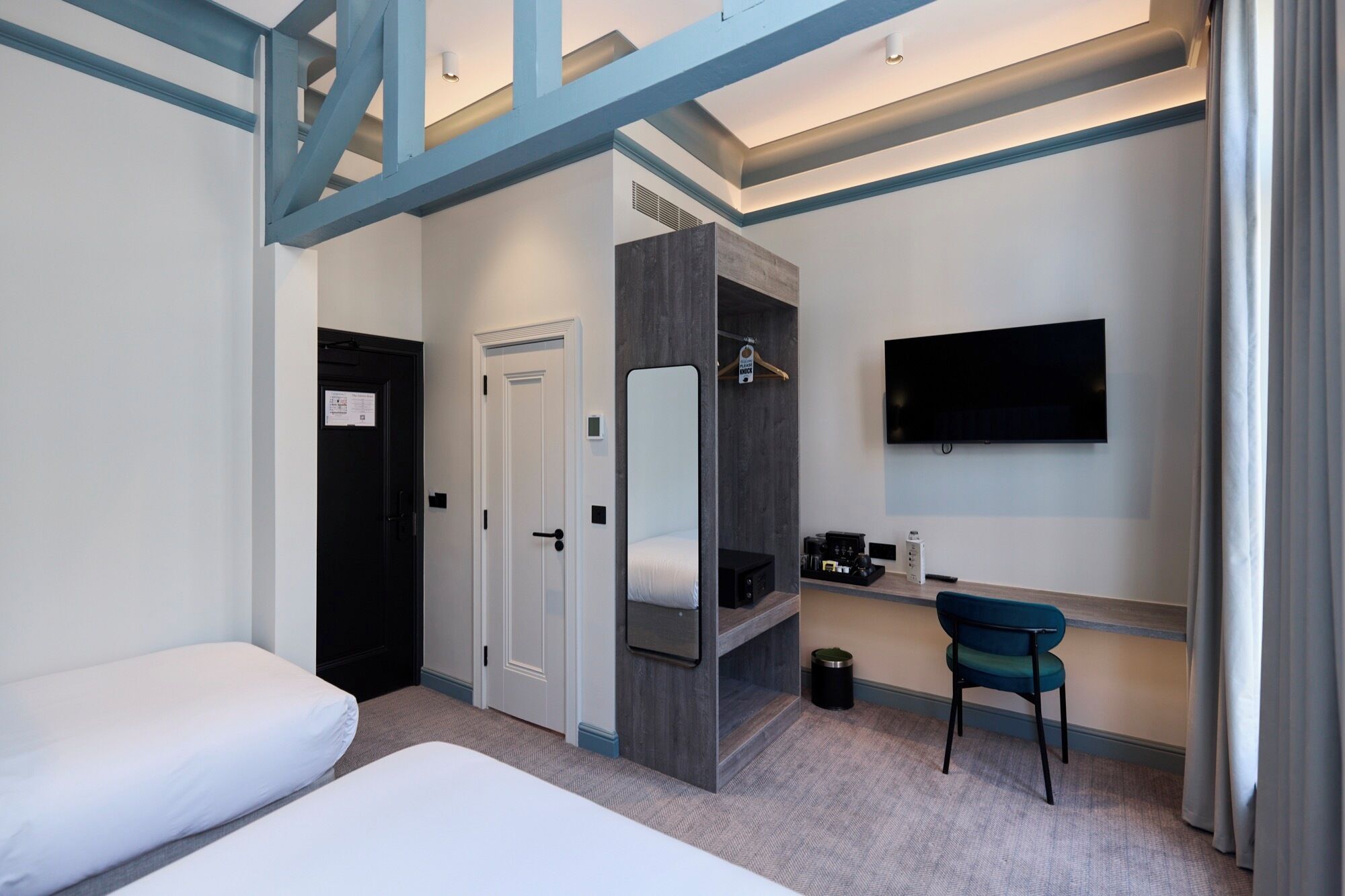 Ett hotellrum med en säng, ett skrivbord, en stol, en tv och en garderob.