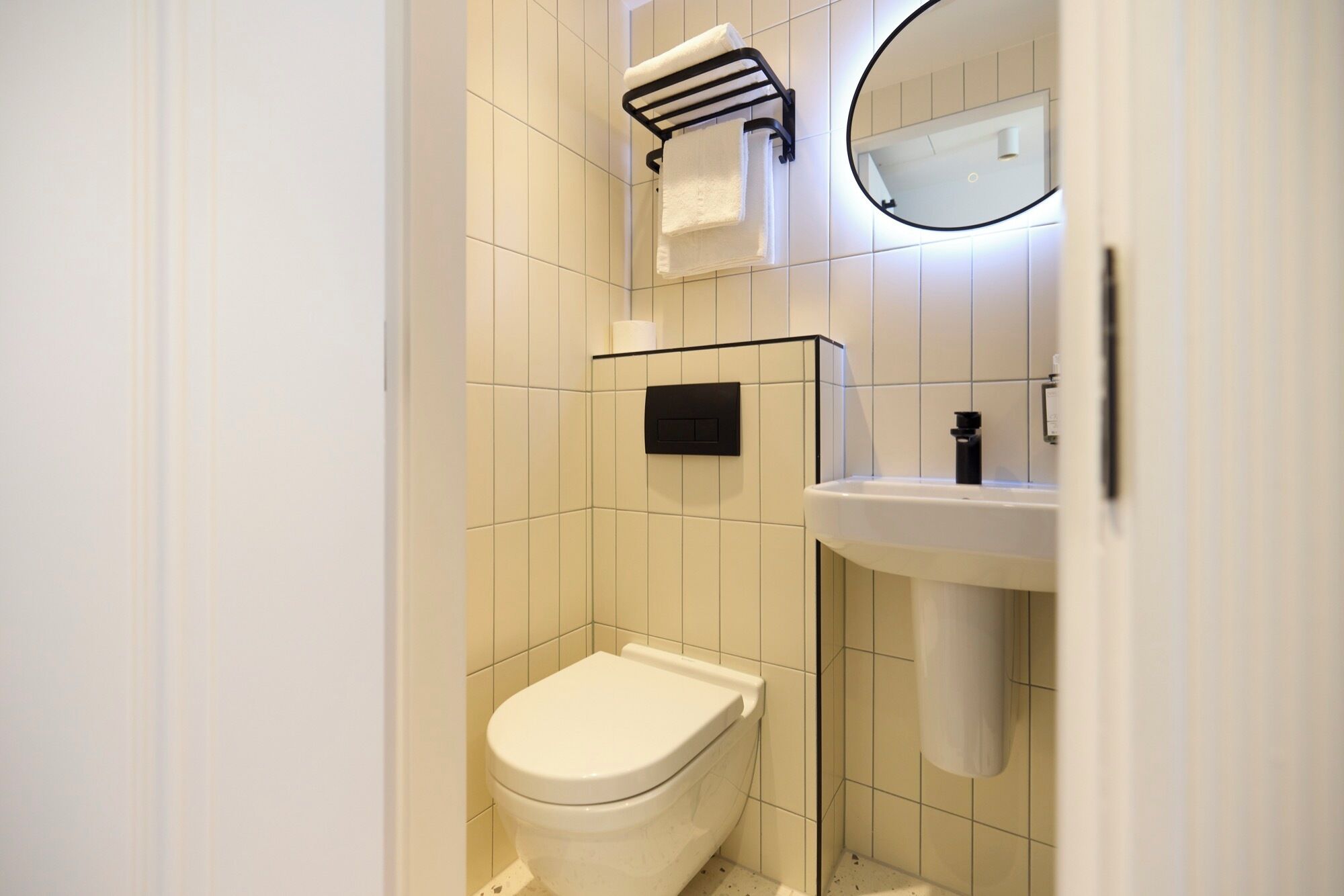 A modern bathroom with a toilet, a sink, and a towel rack.