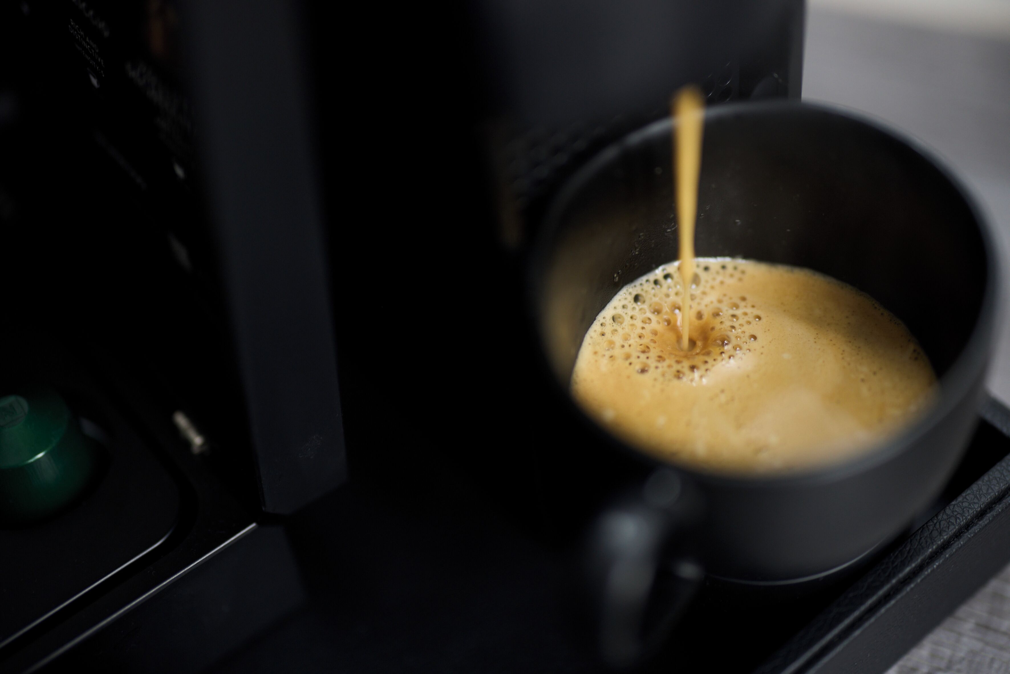 A coffee machine dispensing coffee into a black cup.