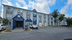 A multi-story residential building with a blue entrance, parking lot, and a clear sky. - Microtel Inn by Wyndham Atlanta Airport (College Park)